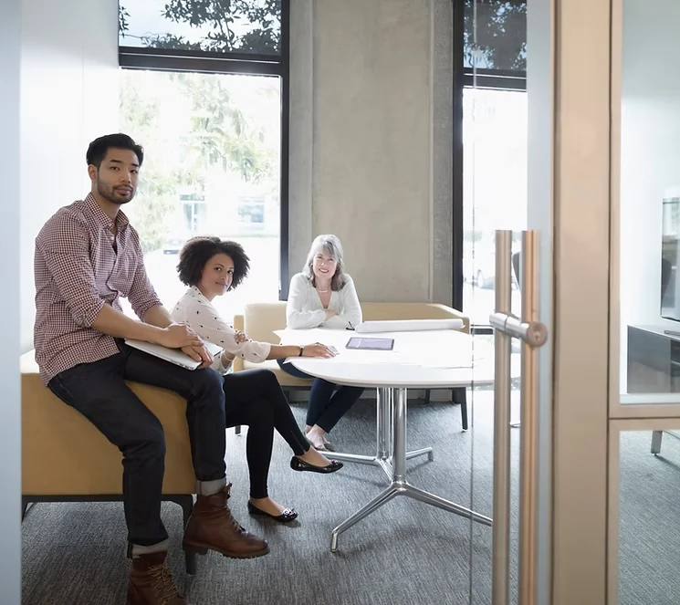 Three people meeting around a table in a bright office